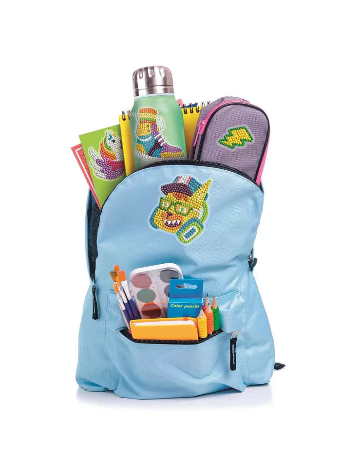 Light blue backpack and school supplies decorated with colorful gemstone art stickers of a cat, shoe, and unicorn.