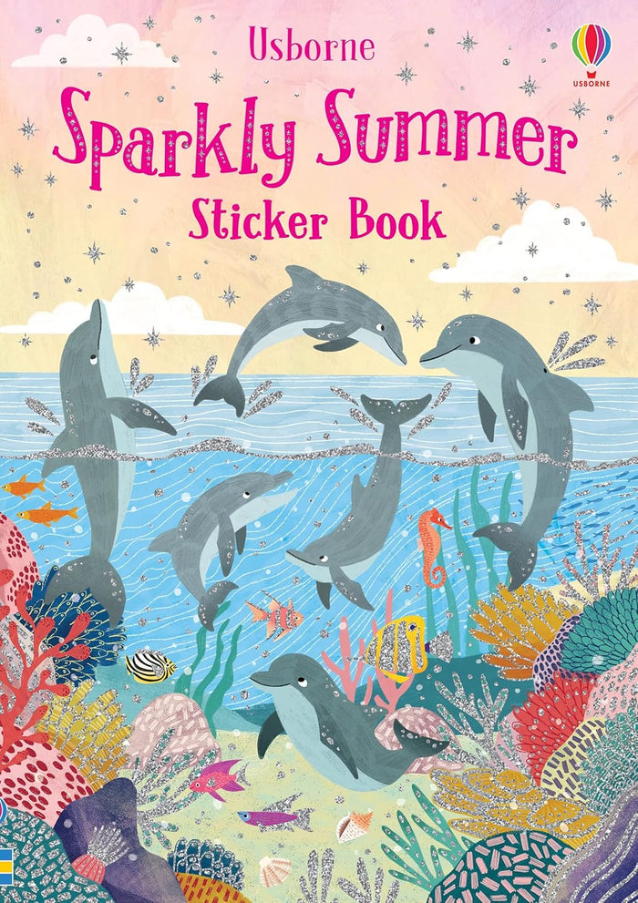 Pink sparkly book cover with grey dolphins leaping and swimming in a blue ocean above a vibrant coral reef with fish.