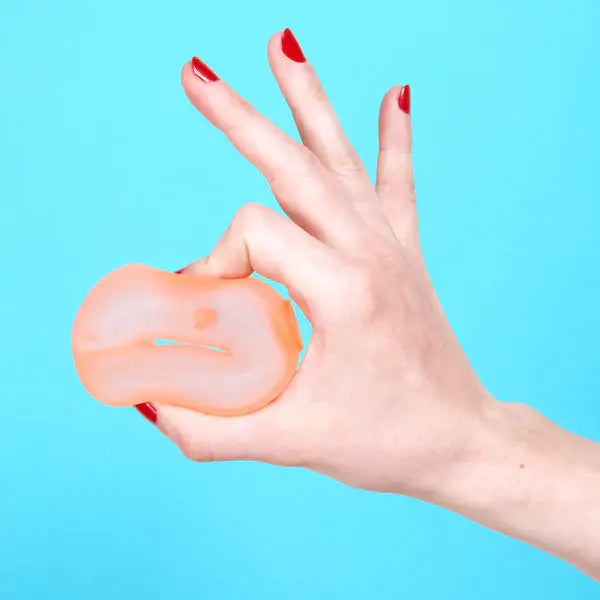 Translucent peach memory gel loop being pinched by a hand with red fingernails on a bright blue background.