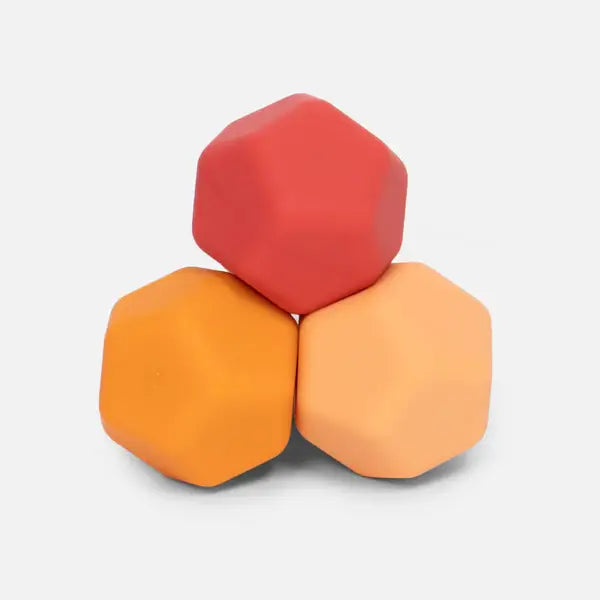 Three faceted, matte silicone magnets in red, orange, and peach, stacked in a pyramid shape.