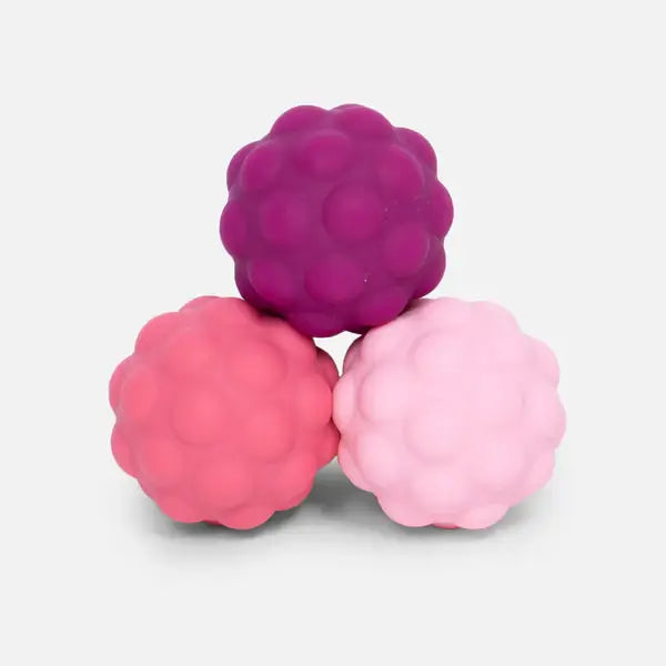 Three bumpy silicone spheres in dark purple, pink, and light pink, stacked in a pyramid.