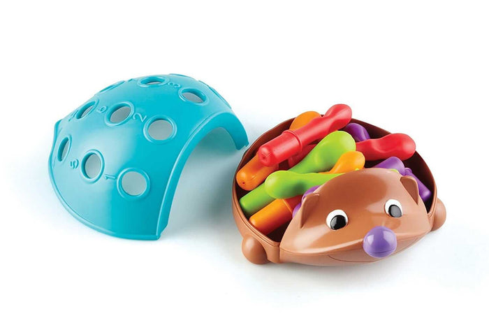 Brown plastic hedgehog base filled with colorful pegs next to a blue dome-shaped shell with numbered holes.