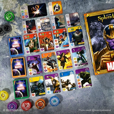 Marvel game box featuring Thanos, superhero cards, and colorful circular tokens on a grey surface.