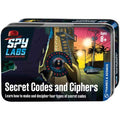Metal tin box featuring spy-themed artwork of a person using a cipher wheel in a city alley at sunset.