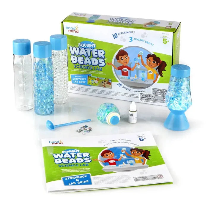 Green box science kit with blue sensory bottles, beads, a mood lamp, and experiment guide on a white background.