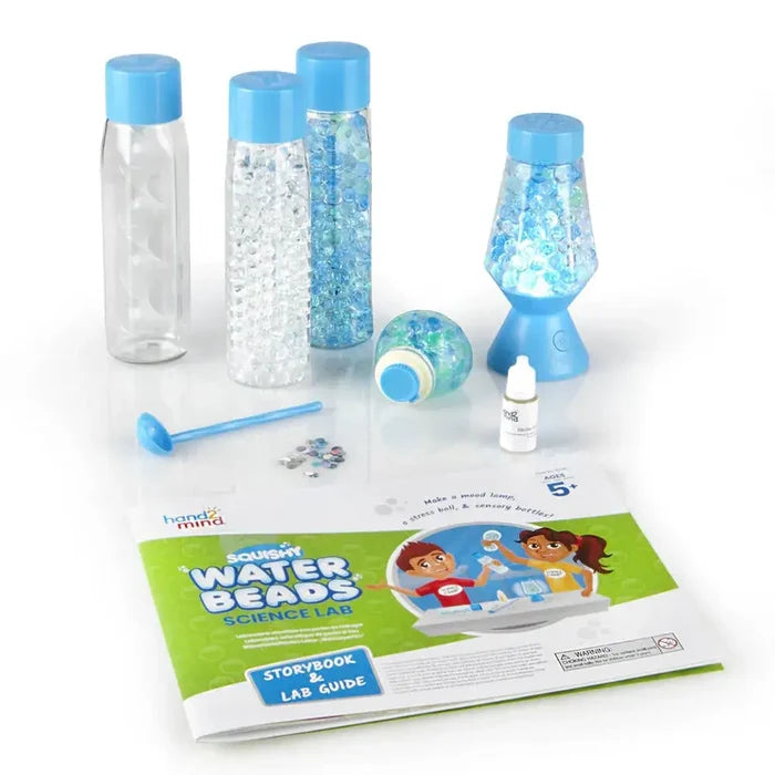 Science kit with blue and white water beads in bottles, a lava lamp, stress ball, scoop, and colorful lab guide.
