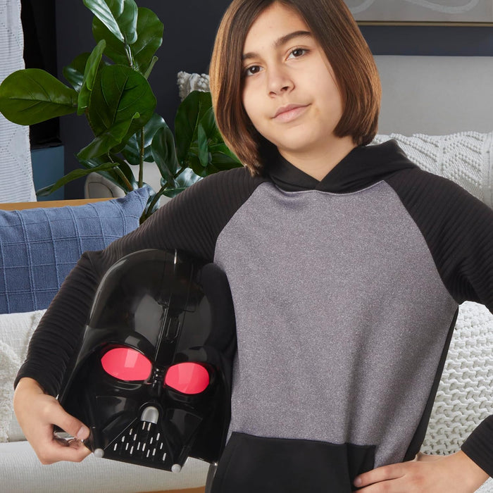 Child holding a black Darth Vader electronic mask with glowing red eyes and silver grill details.