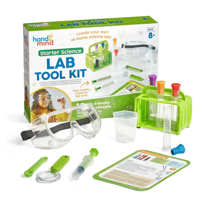 Kids' science kit box with a green test tube rack, safety goggles, beaker, and experiment instruction cards.