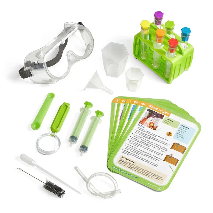 Science set with goggles, test tubes in a green rack, syringes, a magnifier, beakers, and colorful activity cards.