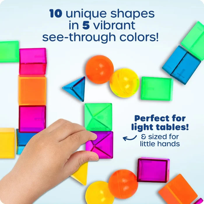 Child's hand arranging colorful, translucent 3D geometric shapes like spheres, cubes, and pyramids.