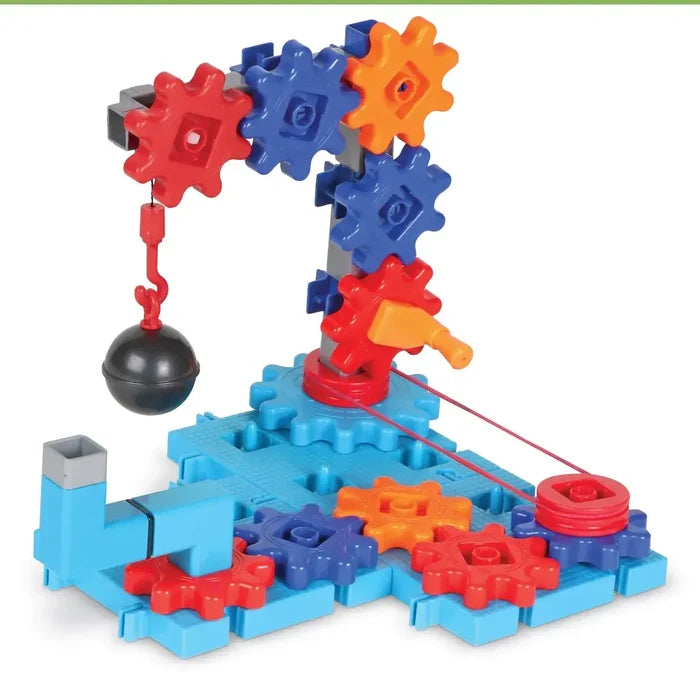 Colorful gear-based toy crane with red, blue, and orange gears on a blue base, featuring a swinging wrecking ball.