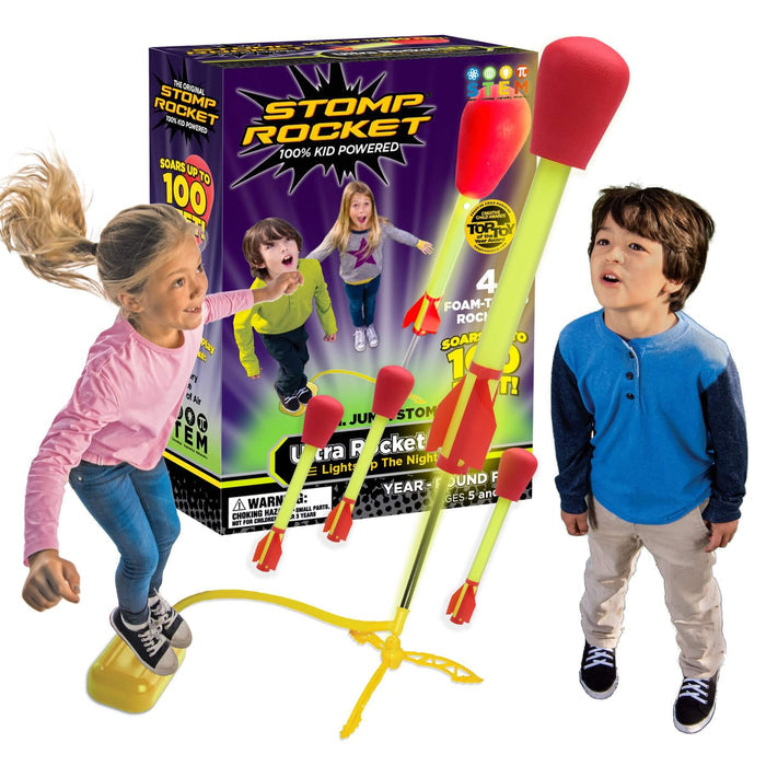 Children launching yellow and red foam rockets from a yellow base next to the purple and black Stomp Rocket toy box.