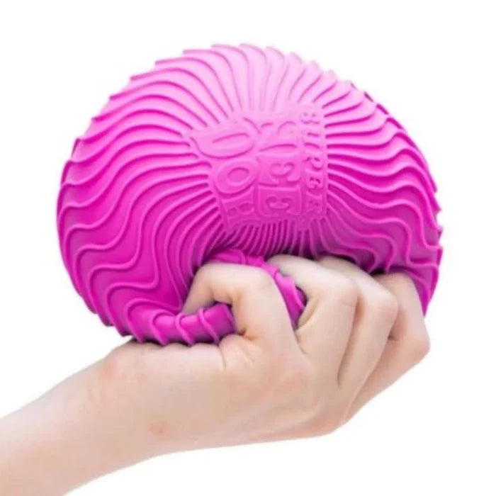 Hand squeezing a large, bright pink spherical stress ball with a raised wavy ripple texture.