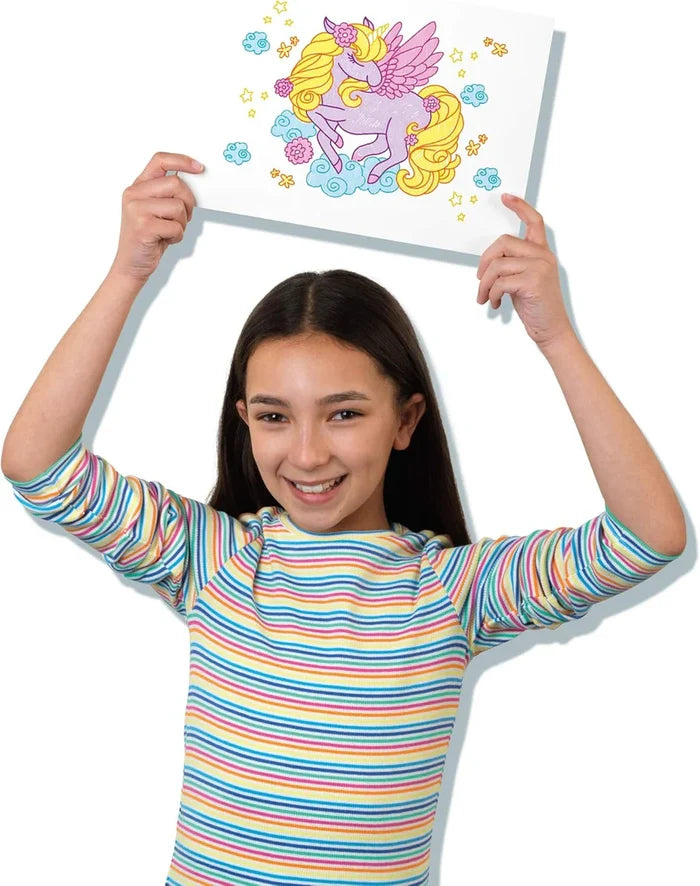 Smiling girl holding up a colorful drawing of a purple winged unicorn with yellow hair and stars.