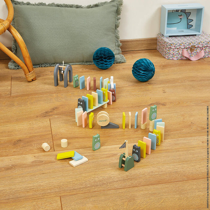 Pastel wooden dominoes and owl blocks arranged in a winding path with play obstacles on a light wood floor.