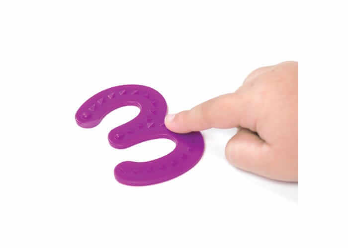 Child's finger touching a purple plastic number three with raised tactile bumps on a white background.