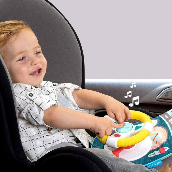 Toddler in a car seat playing with a yellow and white toy steering wheel attached to a colorful fabric activity mat.