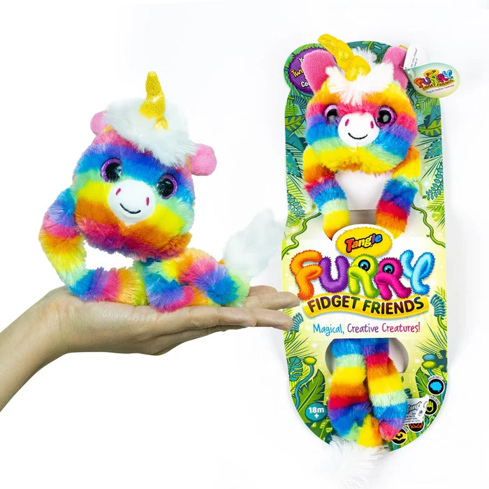 Rainbow furry unicorn fidget toy with a yellow horn, held in a hand next to its colorful retail packaging.