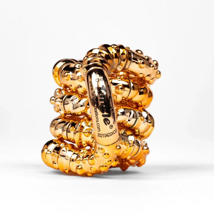 Shiny gold metallic fidget toy with small raised bumps, coiled into a compact knot shape on a white background.