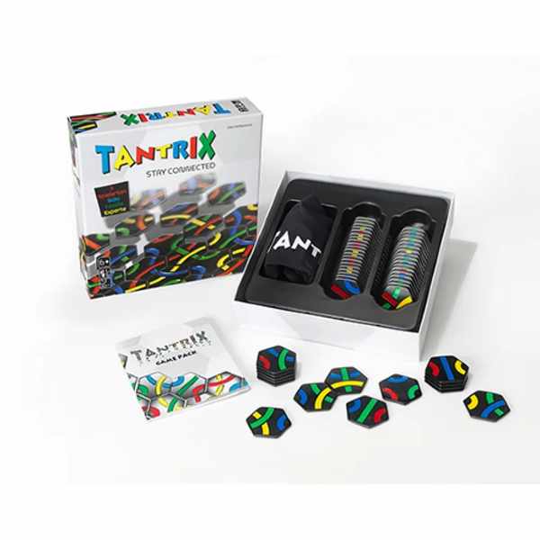 Open game box showing black hexagonal tiles with colorful paths, a storage bag, rulebook, and scattered game pieces.