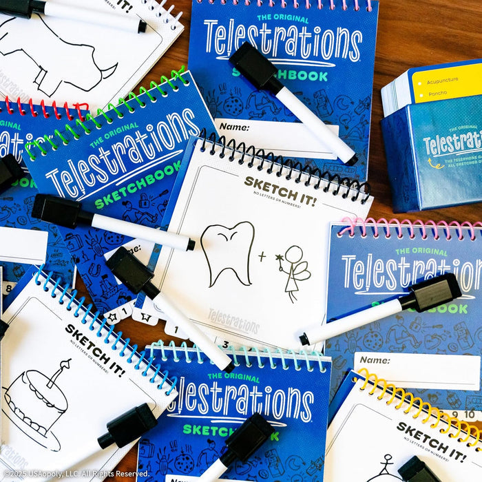 Flat lay of blue Telestrations spiral sketchbooks, dry-erase markers, and simple black ink drawings on white pages.
