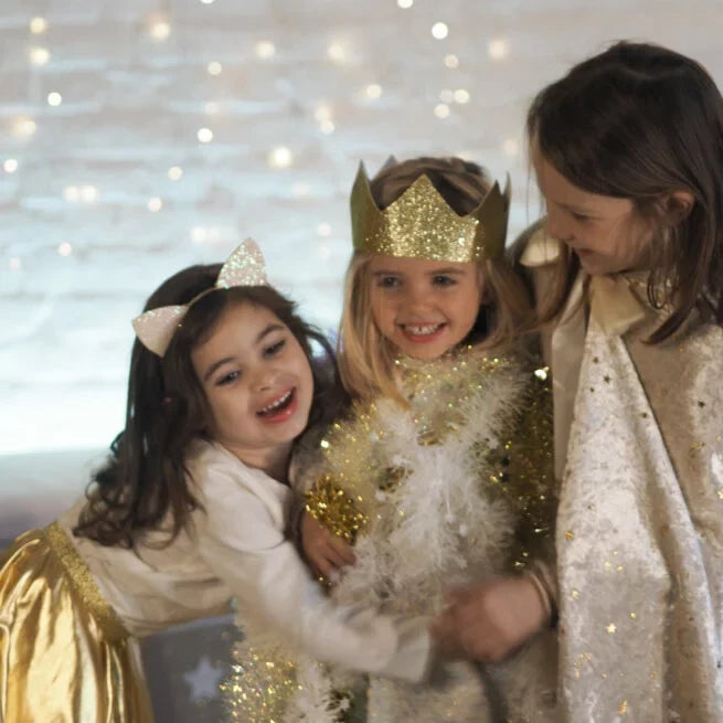 Pointed crown made of sparkling gold glitter, worn by a child smiling with friends in a festive dress-up setting.