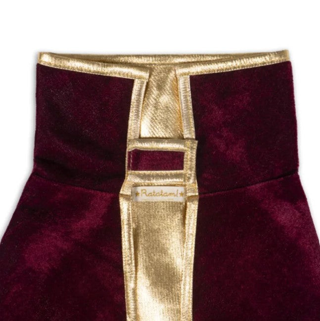 Close-up of a bordeaux velvet garment featuring shiny gold metallic trim and a Ratatam brand label.