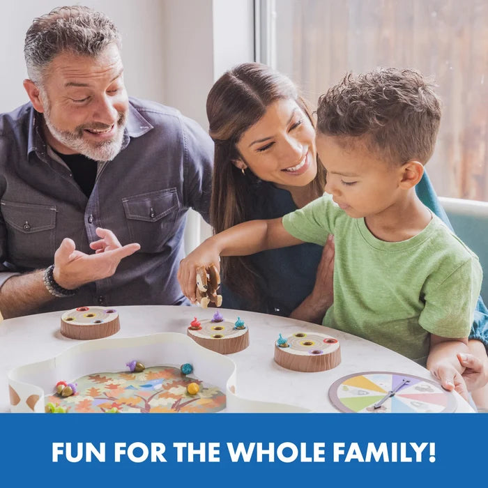 Family playing a board game with a squirrel squeezer, colorful plastic acorns, log-shaped holders, and a spinner.