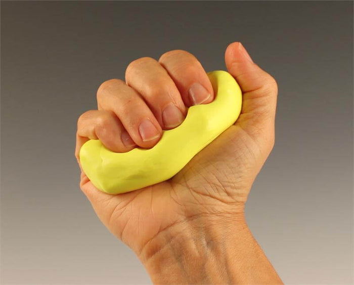 A hand squeezing a thick, oblong piece of bright yellow putty, showing finger indentations in the pliable material.