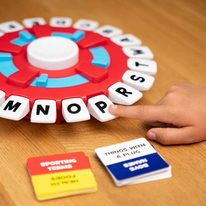 A child's finger presses a letter on a circular red and white alphabet game board next to category cards.