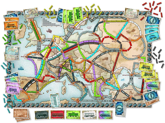 Overhead view of a board game map of Europe with colorful train routes, cards, and small plastic train pieces.