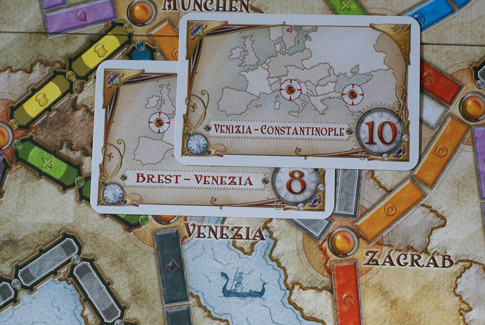 Two destination cards on a colorful board game map featuring illustrated train routes, city names, and point values.