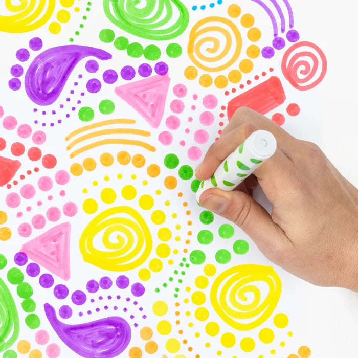 Hand using a white dot marker to create vibrant patterns of colorful dots, swirls, and shapes on white paper.