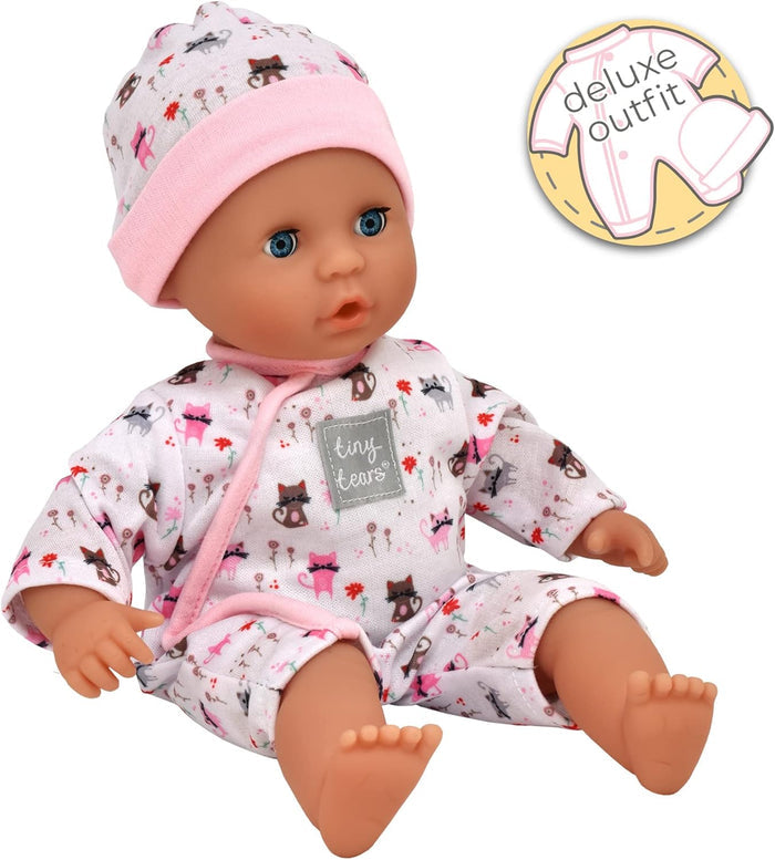 Baby doll with blue eyes wearing a pink and white cat-patterned romper and beanie, sitting on a white background.