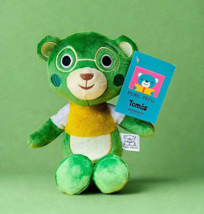 Green plush teddy bear wearing embroidered glasses and a yellow shirt, with a blue product tag on a green background.
