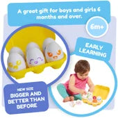 Yellow plastic egg carton with six white toy eggs showing colorful faces, with a baby girl playing with the set.