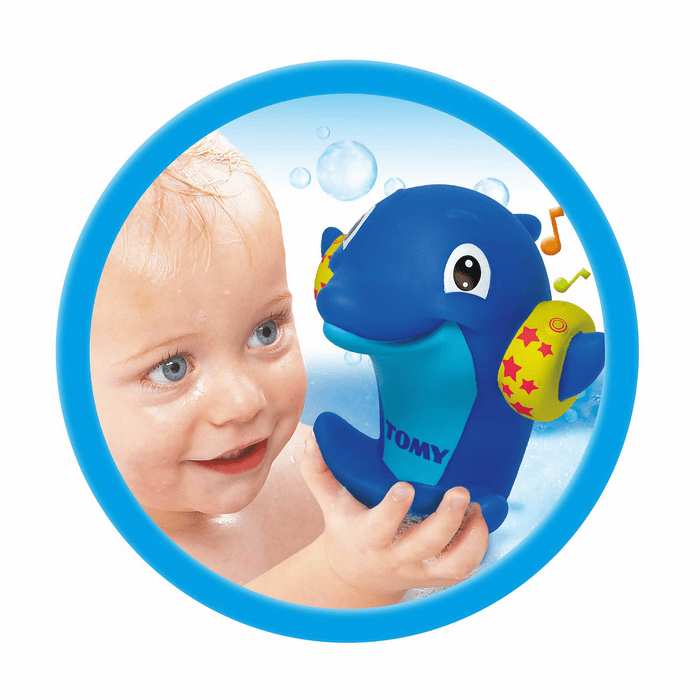Smiling baby holding a blue dolphin bath toy with yellow star armbands and music notes in a circular frame.