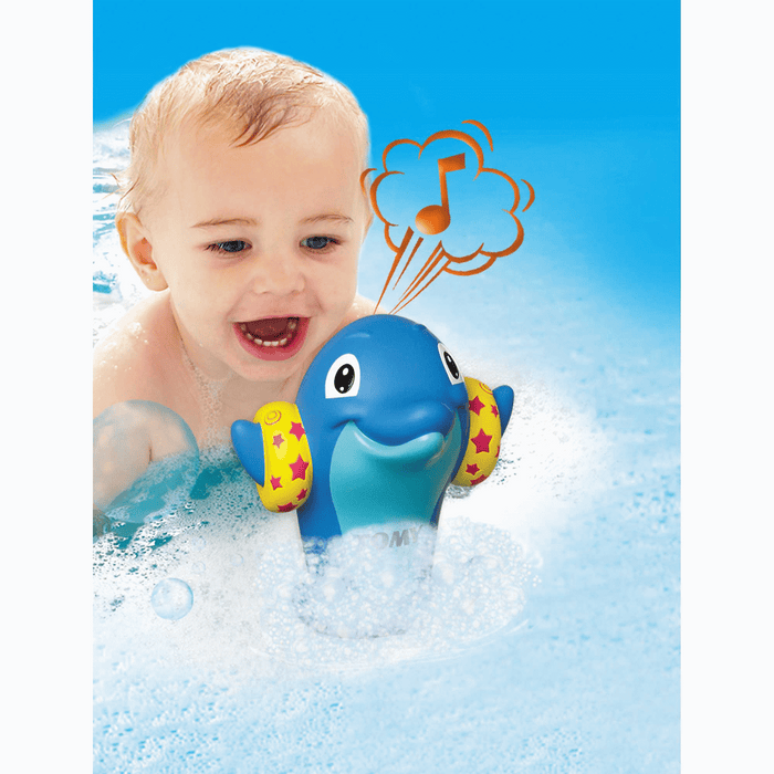 Happy baby in a bath with a blue dolphin toy wearing yellow star armbands and a musical note graphic.