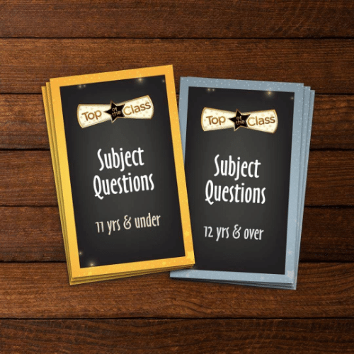 Gold and silver subject question cards for ages 11 and under and 12 and over on a dark wood surface.