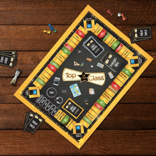 Yellow and black school-themed board game with cards, tokens, and a sand timer on a dark wood background.