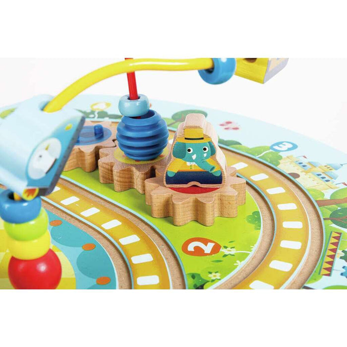 Close-up of wooden gears with an elephant piece, colorful bead maze, and painted track on an activity table.