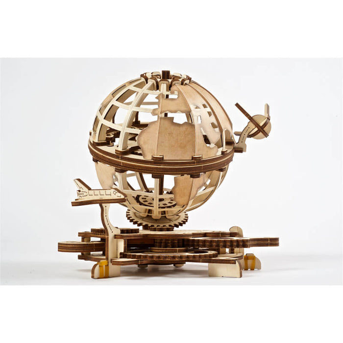 Light wood mechanical globe puzzle with visible gears and two small airplanes circling it on a white background.