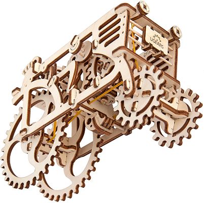 Laser-cut wooden tractor puzzle showing complex internal gears, large spoked wheels, and a yellow rubber band.