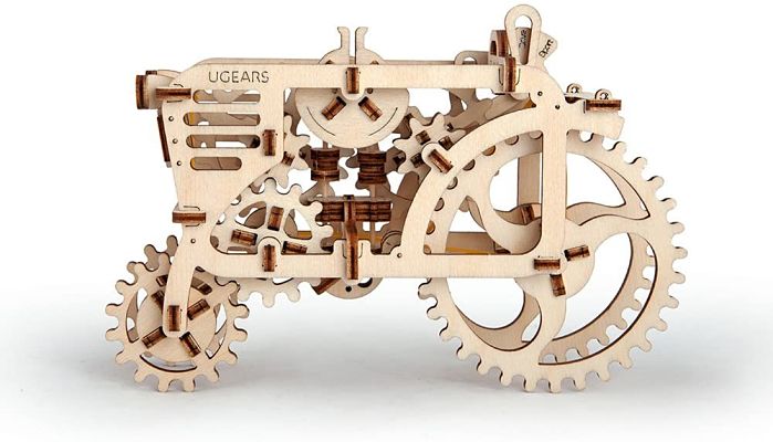 Side profile of an assembled light-wood mechanical tractor model featuring intricate interlocking gears and wheels.