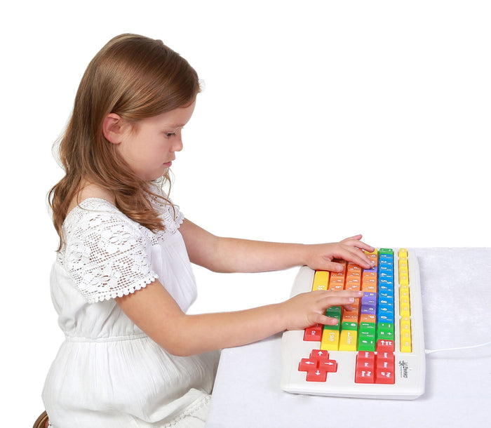 A girl typing on a white keyboard featuring oversized keys in bright yellow, orange, red, green, and blue.