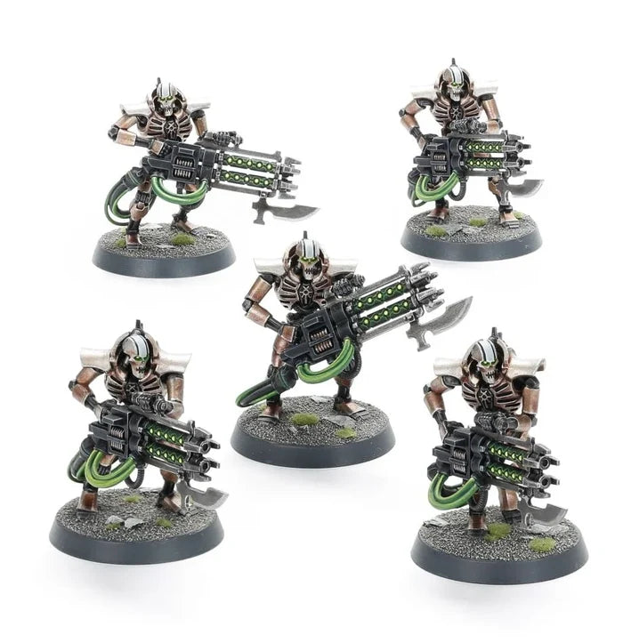 Five bronze and silver skeletal robot figures with glowing green bladed guns on round gravel bases.
