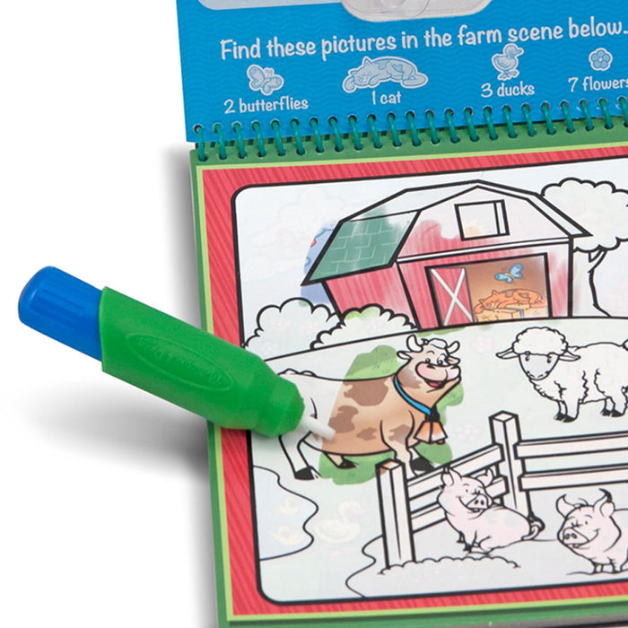 Green water pen coloring a farm scene to reveal hidden colors on a cow and barn in a spiral-bound activity book.
