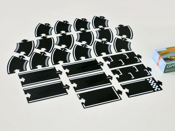 Black flexible road pieces with white markings, curves, and a checkered finish line, shown next to the product box.