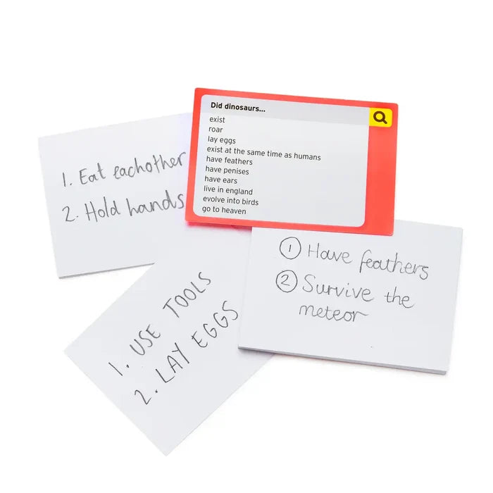 Red game card with dinosaur-themed search prompts and three white pads of paper with handwritten blue ink answers.