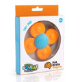 Orange four-petaled toy spinner with a blue spiral suction cup center inside a white retail box with a window.